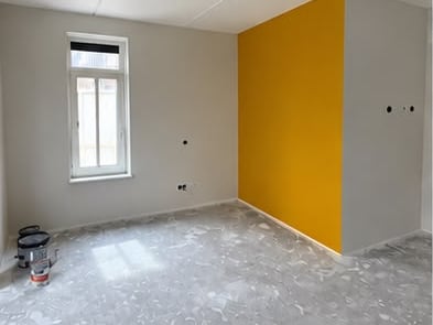 Woonkamer met gele accentwand, strak afgewerkt