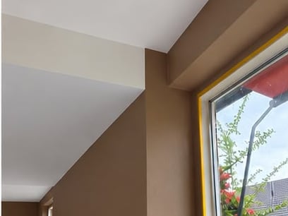 Binnenwand in warm bruin met een wit kozijn